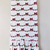 White towel with red bows and green dots pattern on a light gray background