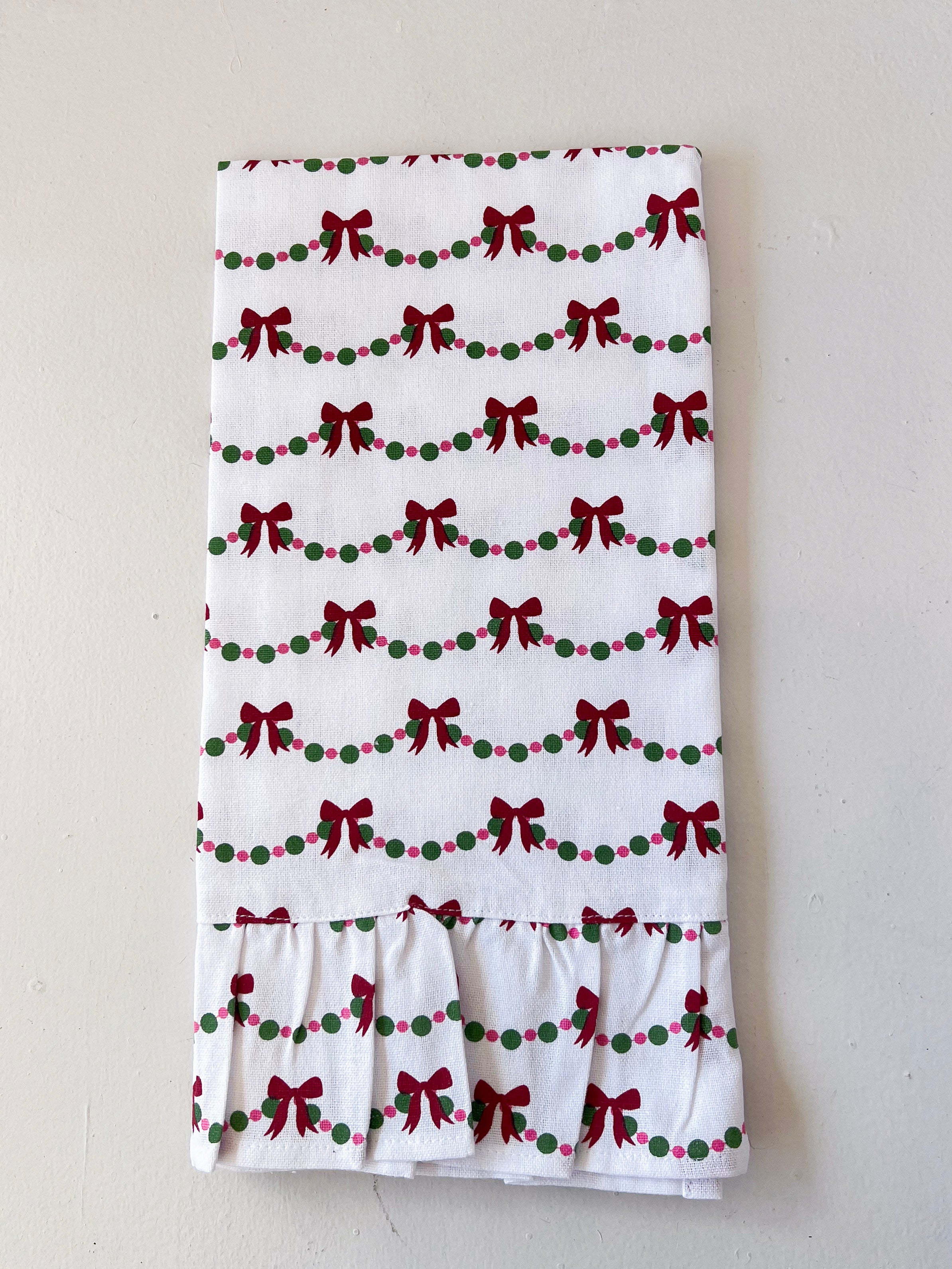 White towel with red bows and green dots pattern on a light gray background