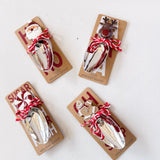 Four Christmas-themed metal spoons on packaging with Santa and reindeer designs on a white background.