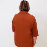 Person wearing a brown coat against a white background
