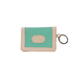 Small green and beige wallet with a key ring on a white background