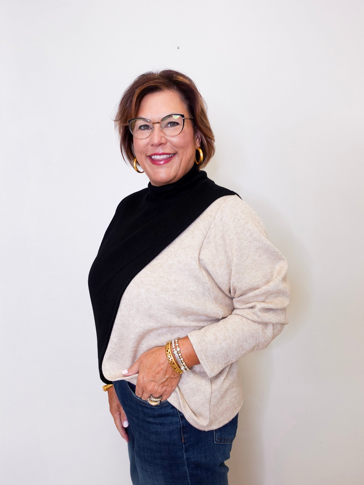 Woman wearing a black and beige sweater with a plain background