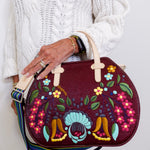 Person holding a colorful embroidered handbag against a white background