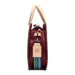Maroon handbag with beige handle and colorful strap on a white background