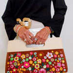 Person holding a handbag with floral design and gold accents