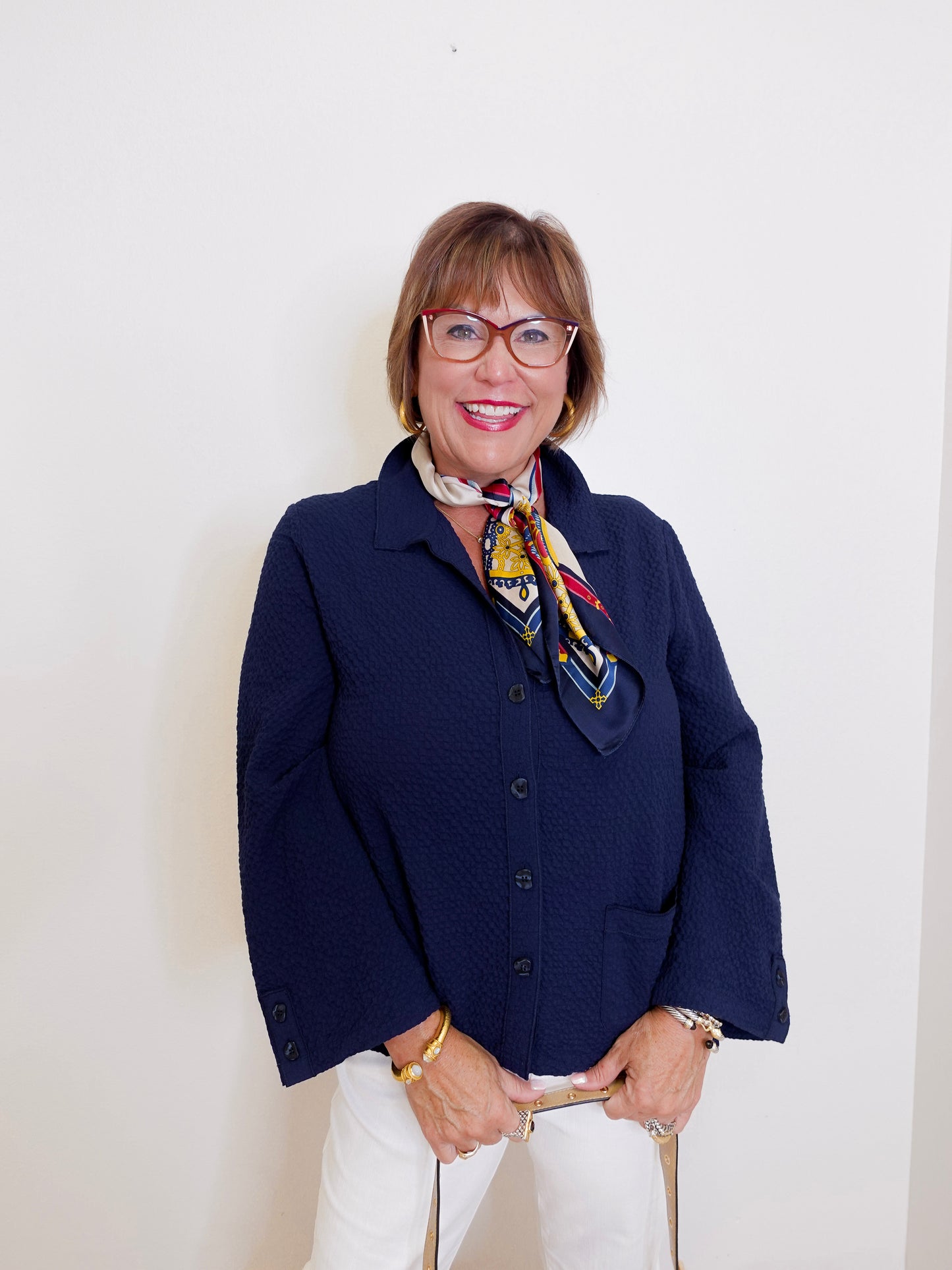 Woman wearing a navy blue jacket with a colorful scarf against a white background