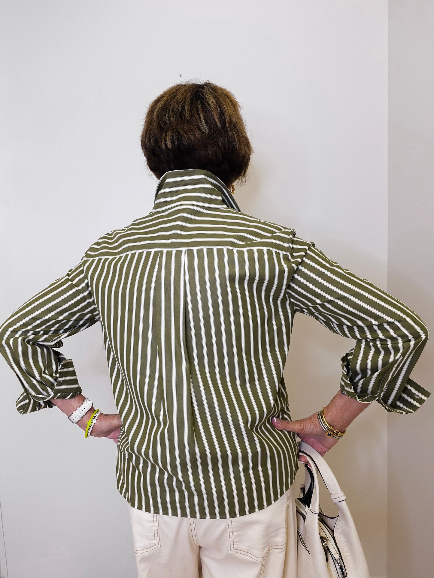 Person wearing a green and white striped shirt against a plain background