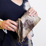 Person holding a gold clutch with a white background