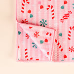 Pink baby blanket with candy cane and peppermint pattern on a beige background