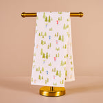 Towel with a Christmas tree and reindeer pattern on a gold towel rack against a beige background