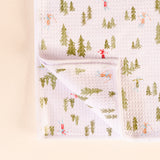 Baby blanket with forest and skier pattern on a light pink background