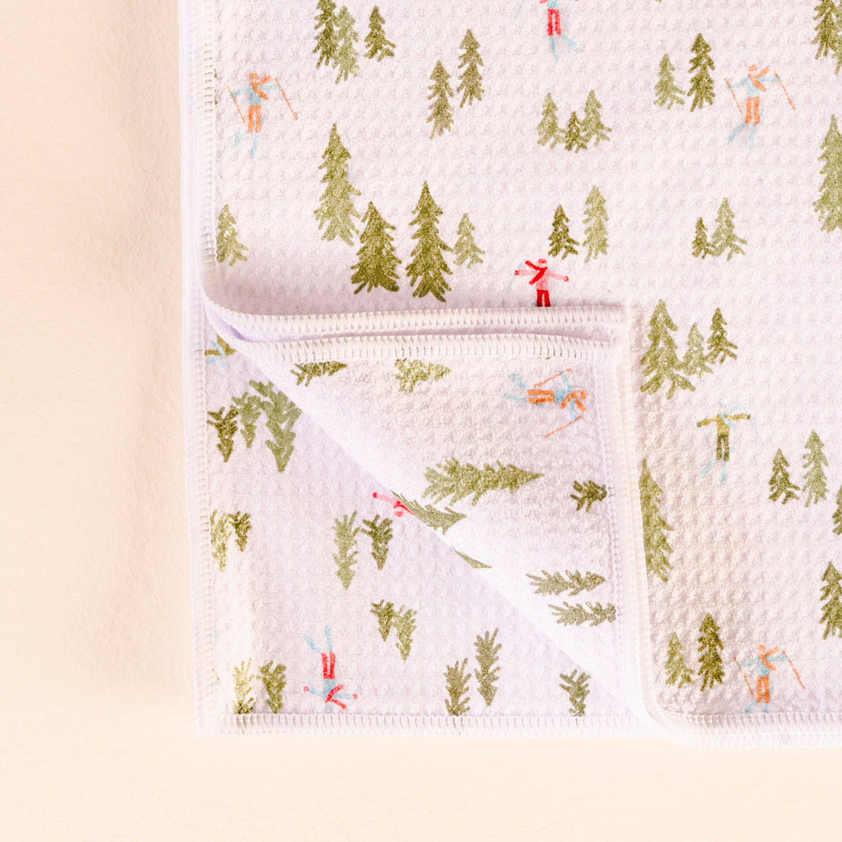 Baby blanket with forest and skier pattern on a light pink background