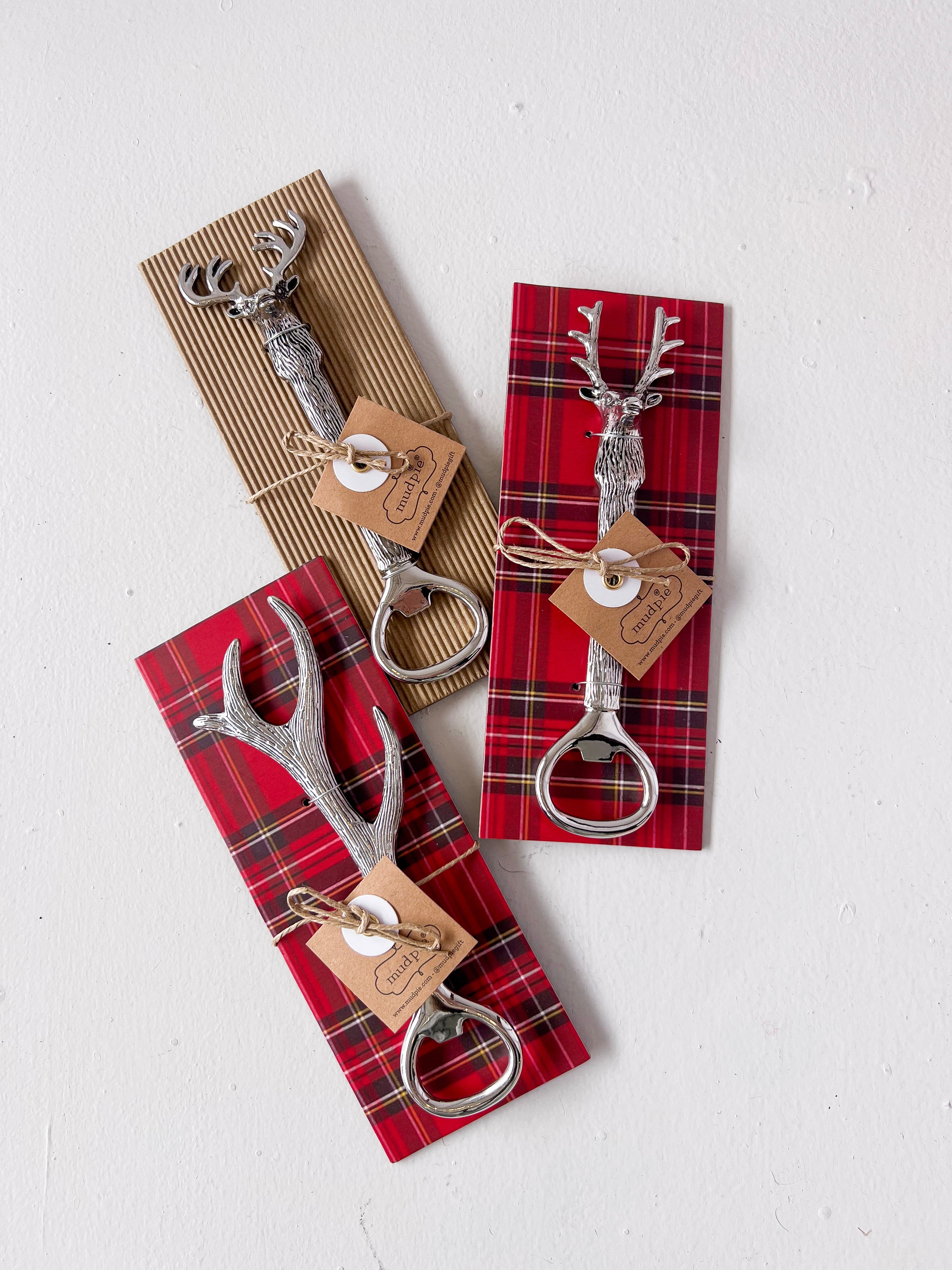 Set of three silver bottle openers with deer heads on plaid paper packaging.