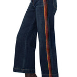 Dark blue jeans with a striped side panel worn by a person on a white background