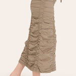 Beige ruched pants worn by a person on a white background