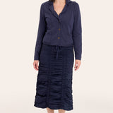 Woman wearing a navy blue outfit with a jacket and skirt on a white background