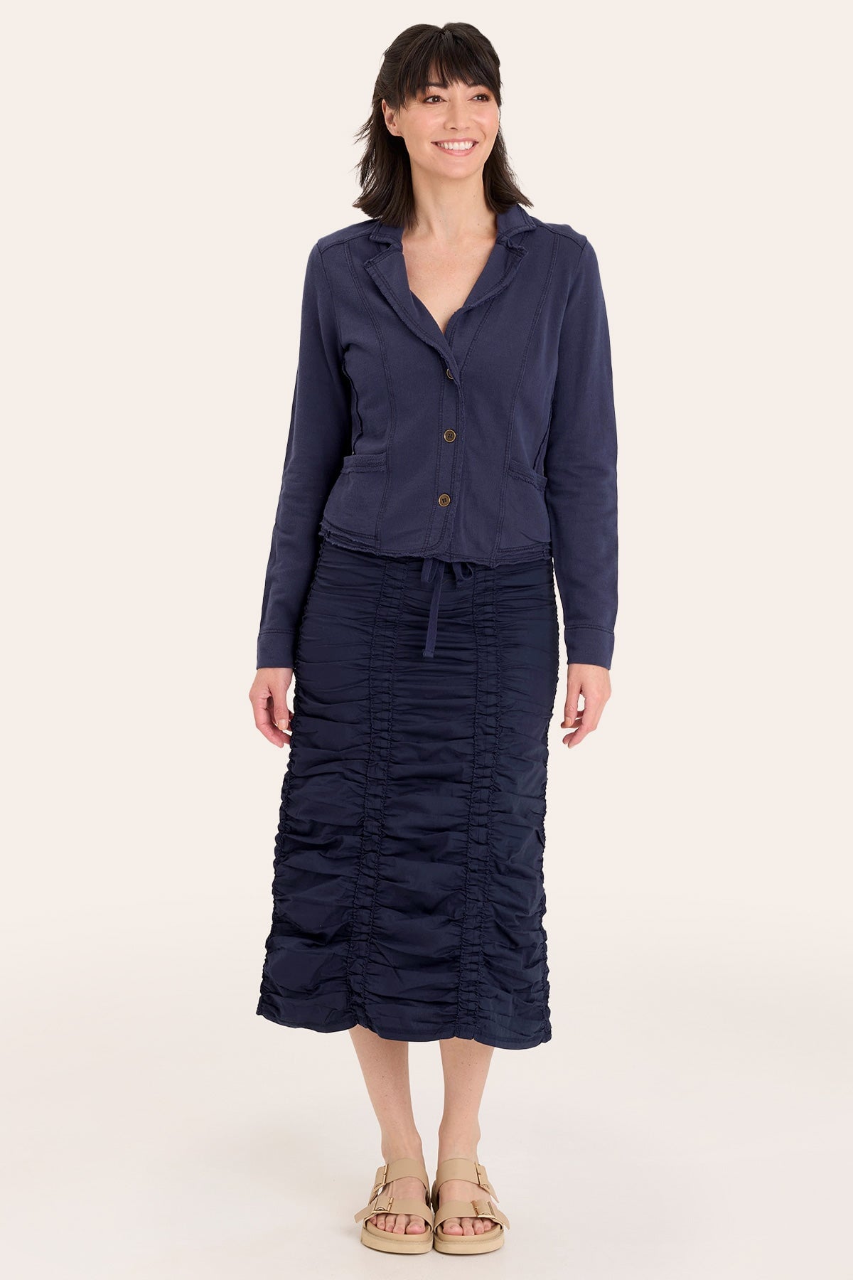 Woman wearing a navy blue outfit with a jacket and skirt on a white background