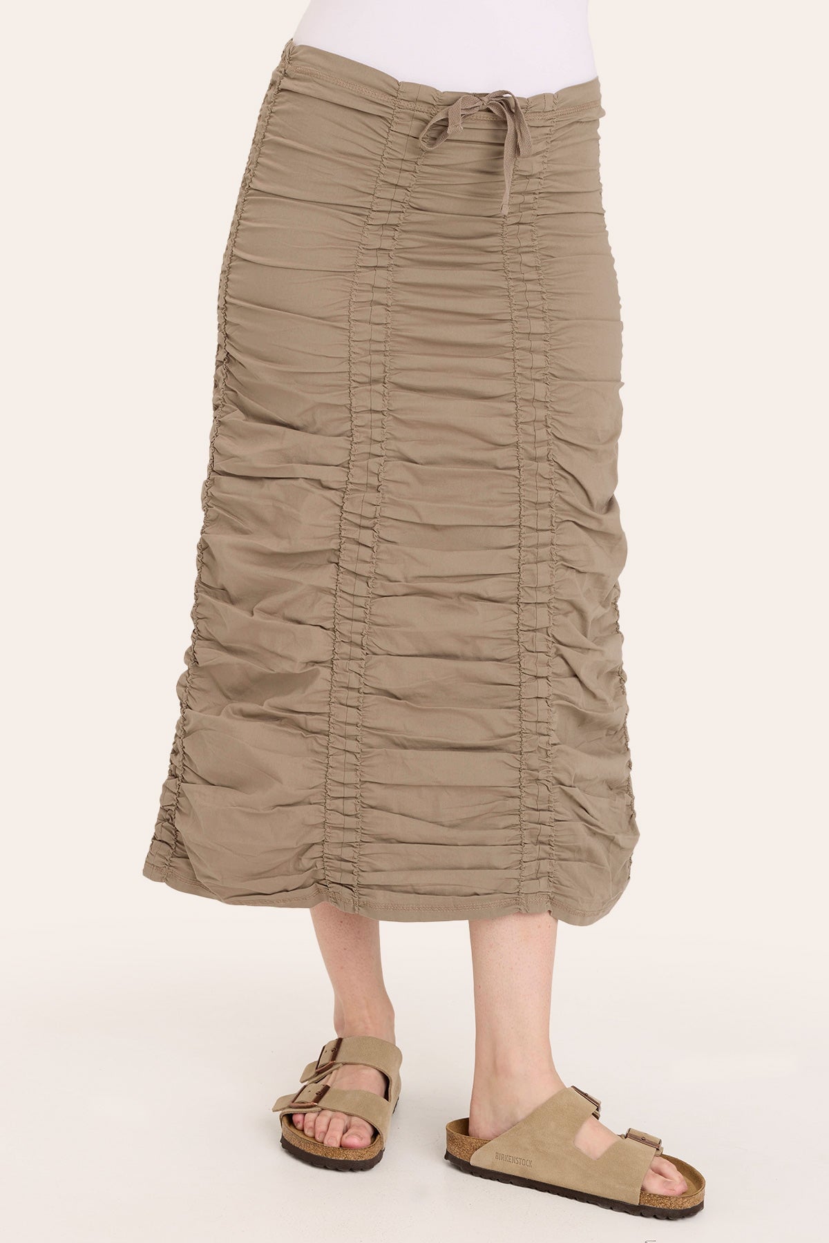 Person wearing a beige ruched skirt on a white background