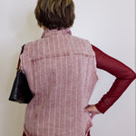 Person wearing a red and white striped vest over a red shirt against a white background