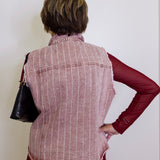 Person wearing a red and white striped vest over a red shirt against a white background