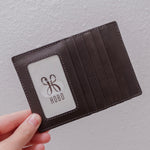 Brown leather wallet held by a hand with 'Hobo' logo on a light gray background
