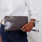 Person holding a brown leather clutch against a white background
