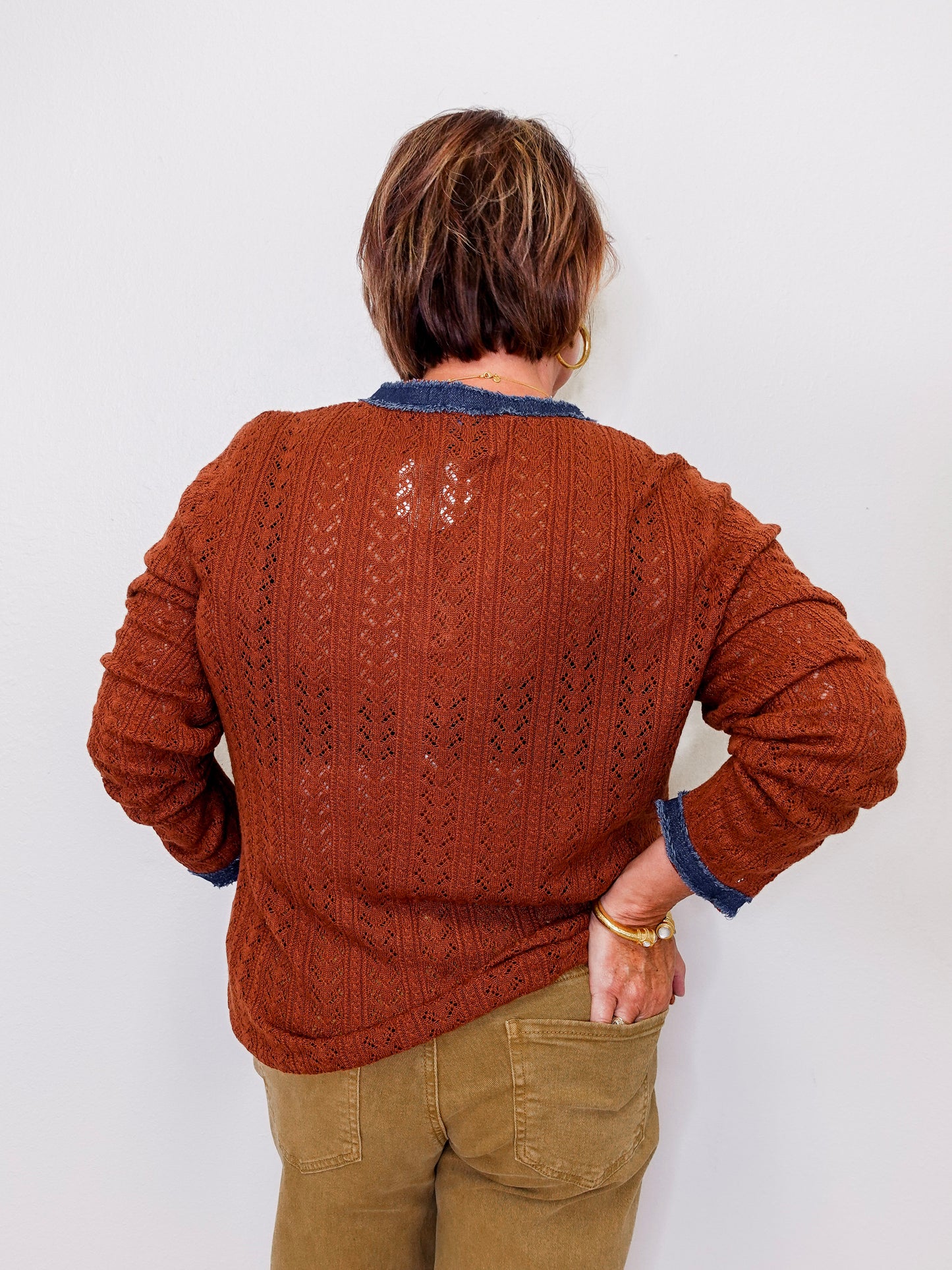 Person wearing a brown knitted sweater with a white background