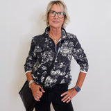 Woman wearing a black and white floral jacket with a plain background