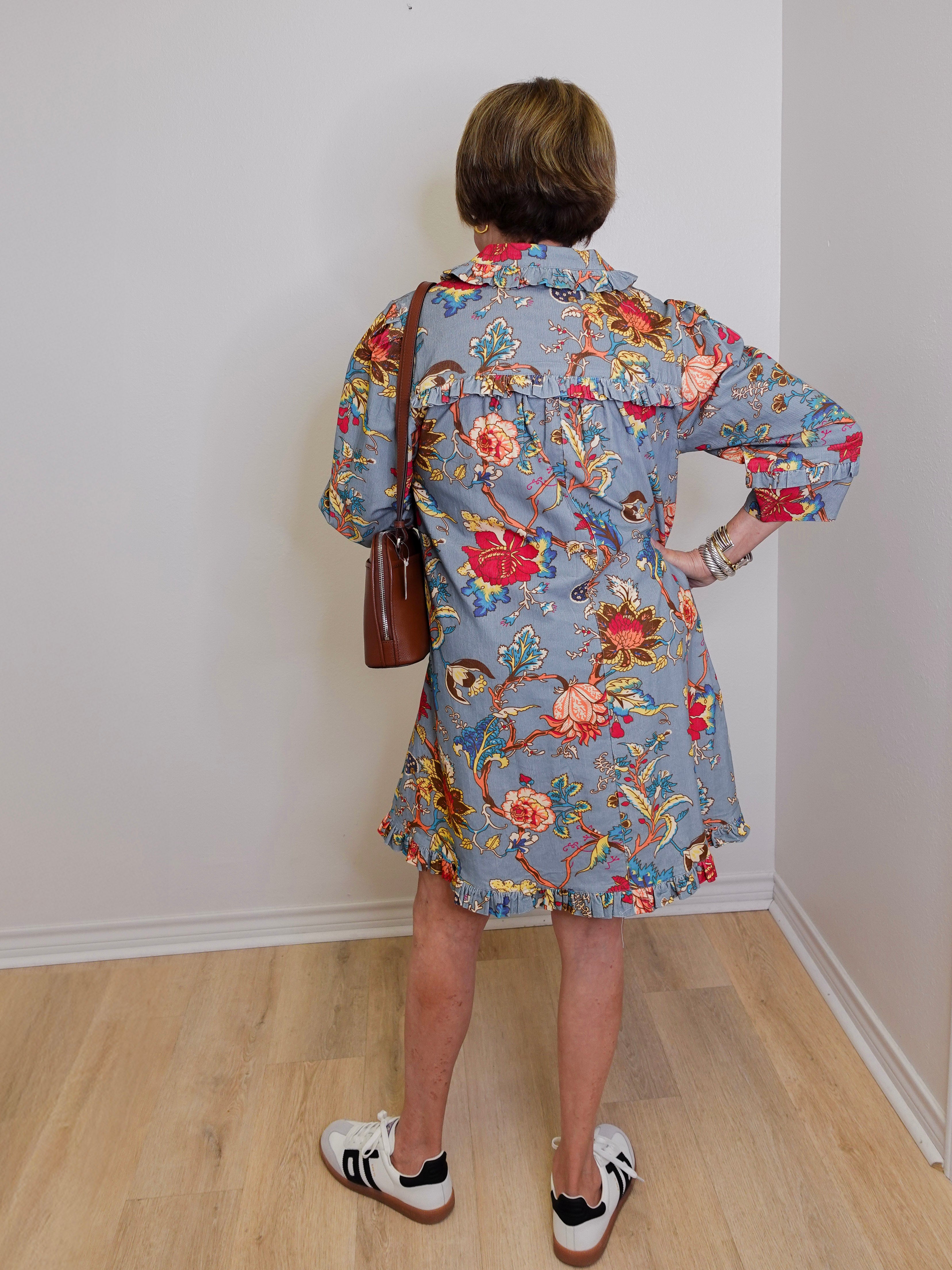 Person wearing a floral dress with a plain white wall background
