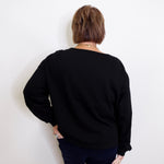 Person wearing a black sweater against a white background