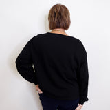 Person wearing a black sweater against a white background