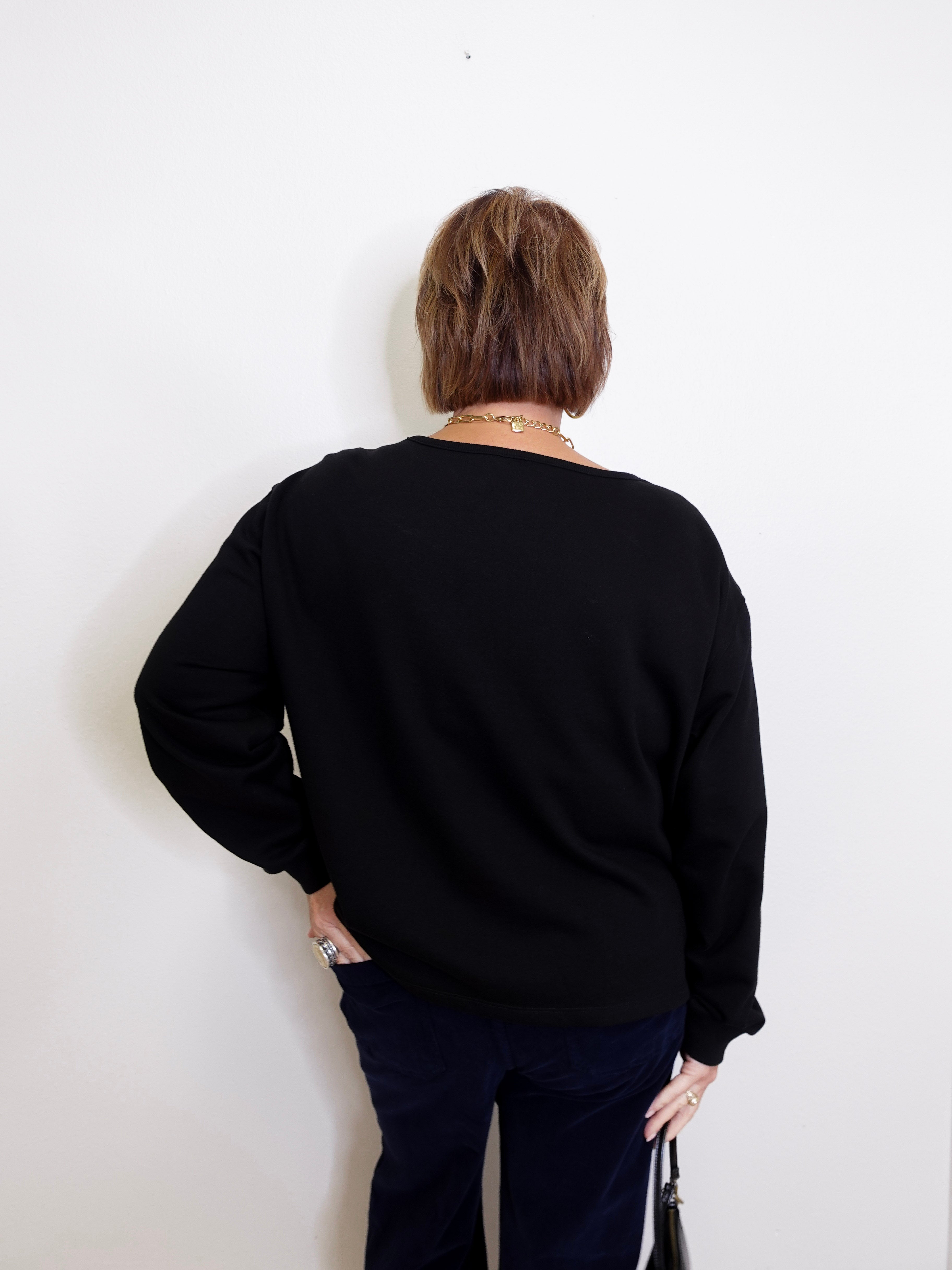Person wearing a black sweater against a white background