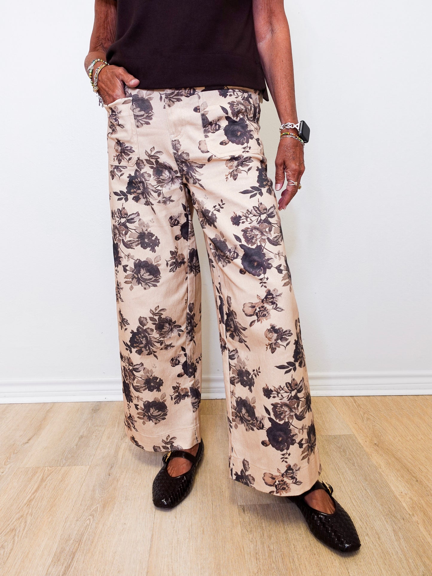 Person wearing floral pants and black shoes on a white background