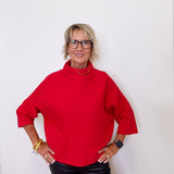 Person wearing a red sweater and black pants against a white background