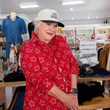 Woman wearing a red star-patterned shirt and white cap in a store setting