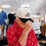 Person wearing a white cap with 'God's Favorite' text in a store setting