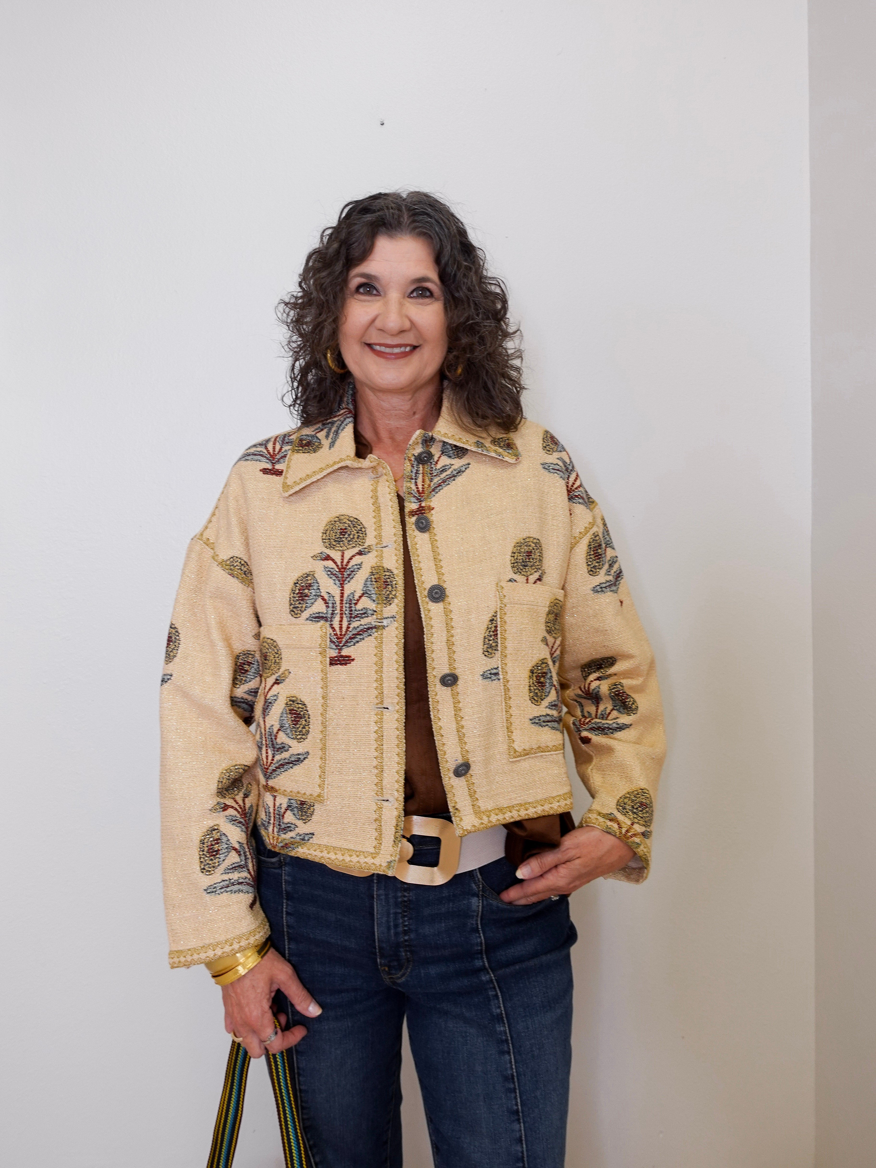 Woman wearing a beige jacket with floral patterns against a white background