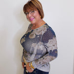 Woman wearing a floral blouse and jeans against a white wall