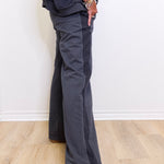 Person wearing dark gray wide-leg pants and white sneakers on a light wooden floor.