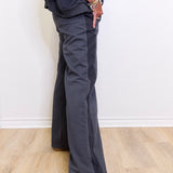 Person wearing dark gray wide-leg pants and white sneakers on a light wooden floor.