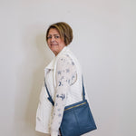 Woman holding a blue bag against a plain white wall