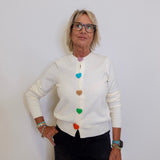 Woman wearing a white cardigan with colorful buttons against a plain background