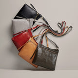 Collection of leather handbags in various colors on a neutral background