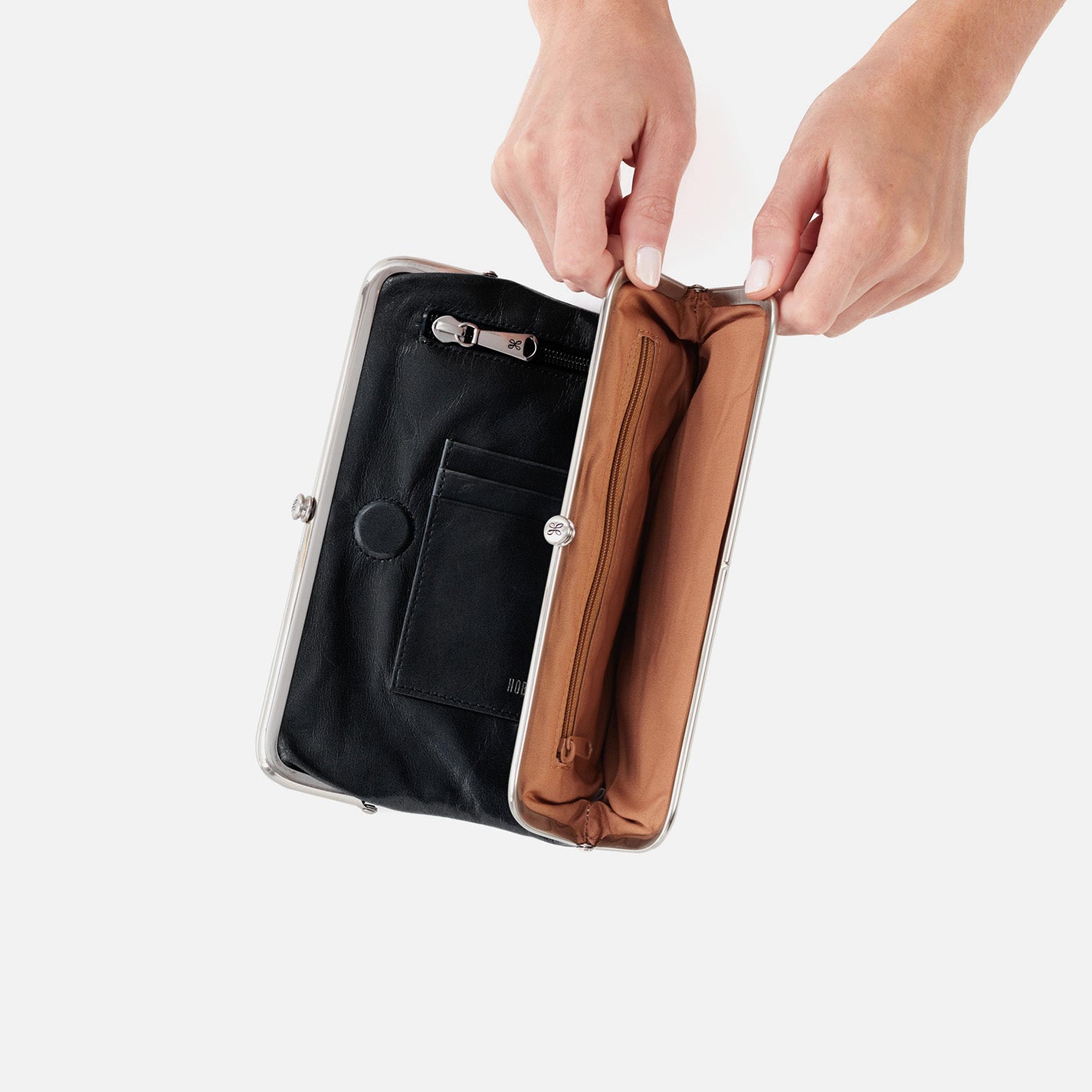 Person opening a black clutch with a brown interior on a white background