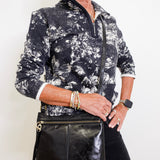 Woman wearing a black and white patterned jacket with a black leather bag.
