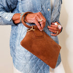 Person holding a brown handbag wearing a blue denim jacket.