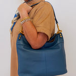 Woman holding a blue handbag against a plain background