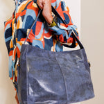 Person holding a blue handbag wearing a colorful jacket.