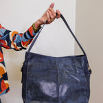 Person holding a blue leather handbag against a plain background