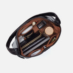 Black leather bag with various items including a bottle and a key on a white background